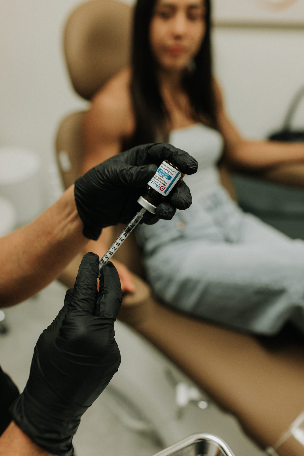 Erica Santana preparing an NAD+ injection with a client seated in the treatment chair